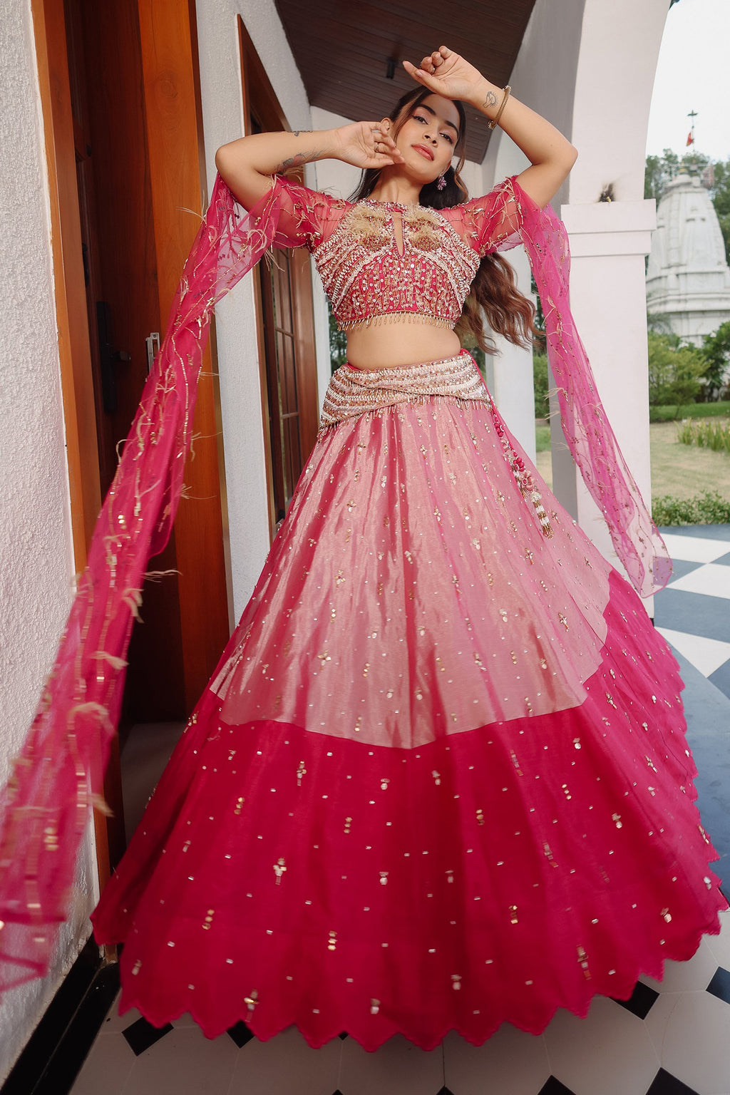 The Fuchsia Pink Ombre Tissue Lehenga Ensemble with High-Neck Keyhole Blouse and Floor-Length Feather Cape Sleeves