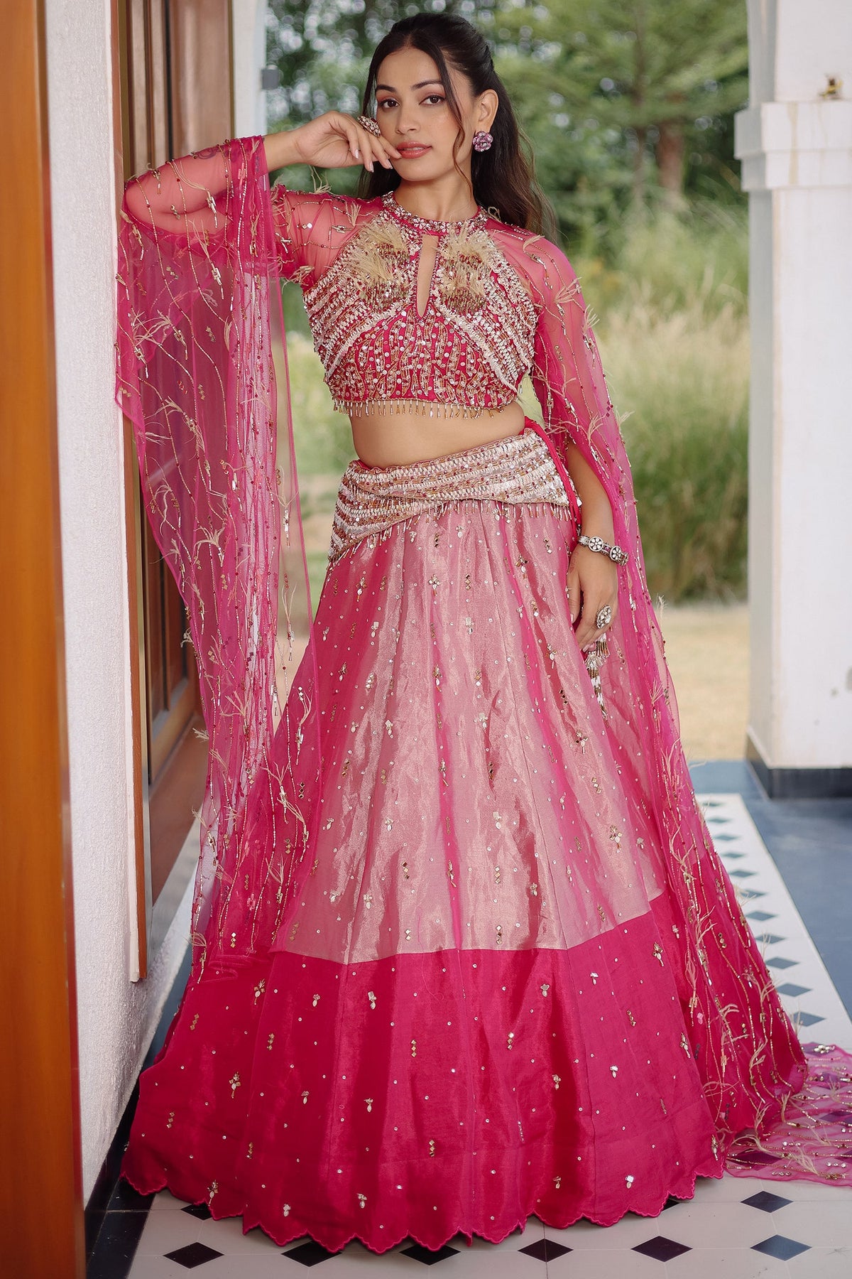 The Fuchsia Pink Ombre Tissue Lehenga Ensemble with High-Neck Keyhole Blouse and Floor-Length Feather Cape Sleeves